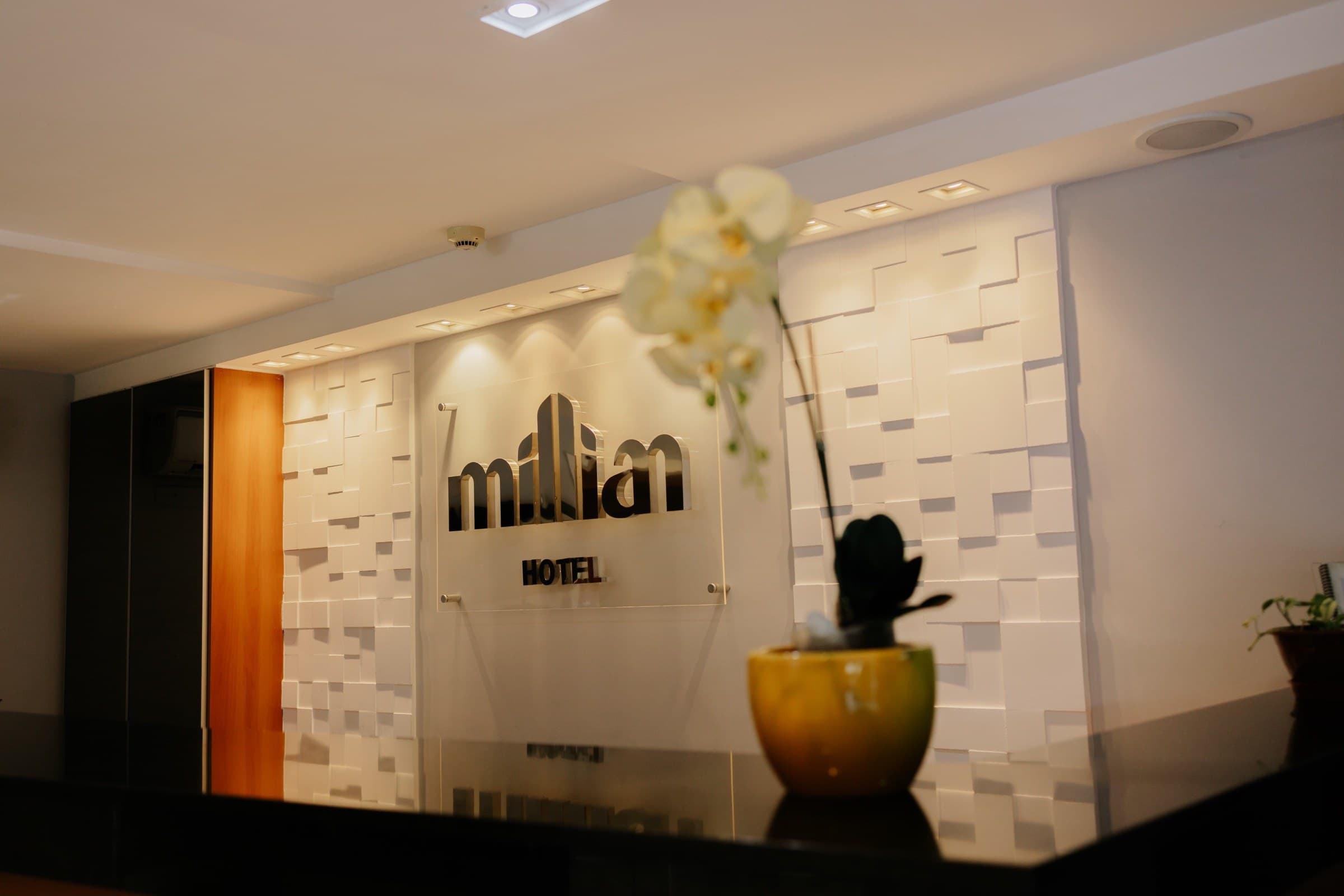 Recepção do Millian Hotel, com o logo iluminado na parede